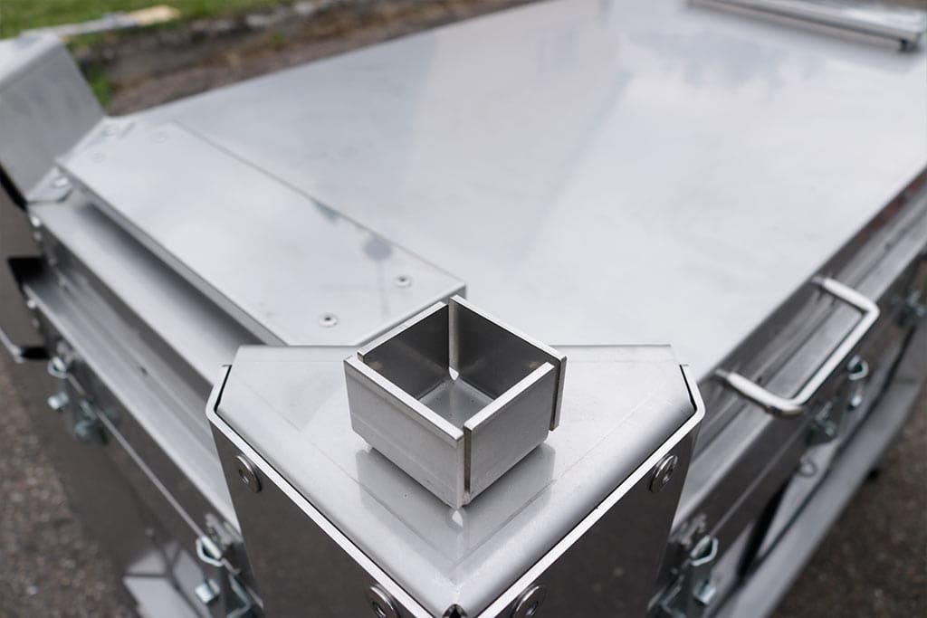 Caixa metálica industrial com acabamento prateado, formato angular e construção rica em detalhes.